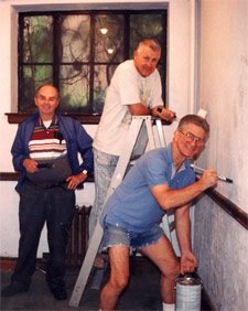 A historical photo of three men repainting the walls of the building.